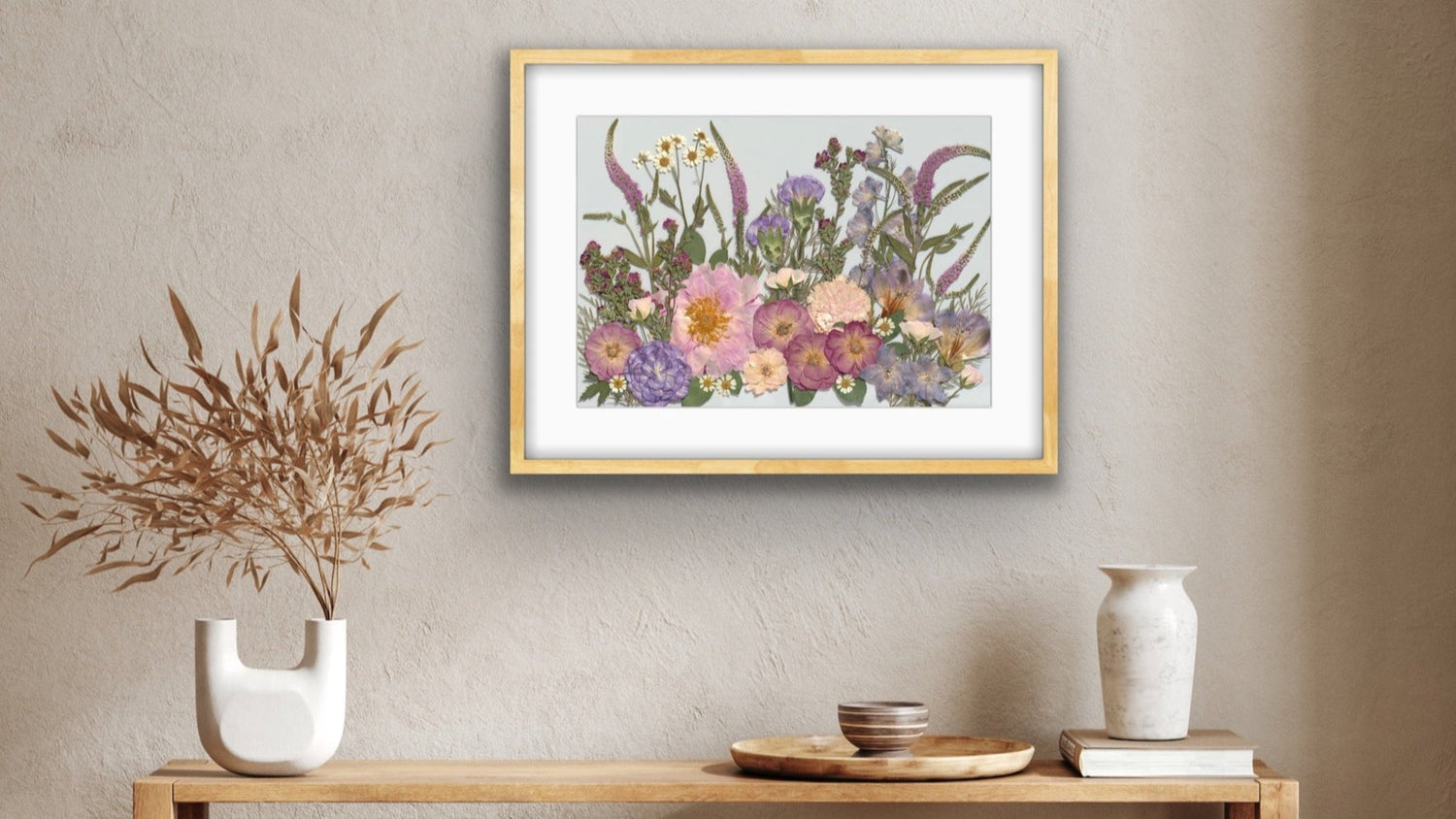 Framed floral artwork on a wall above a wooden console table with decorative items.