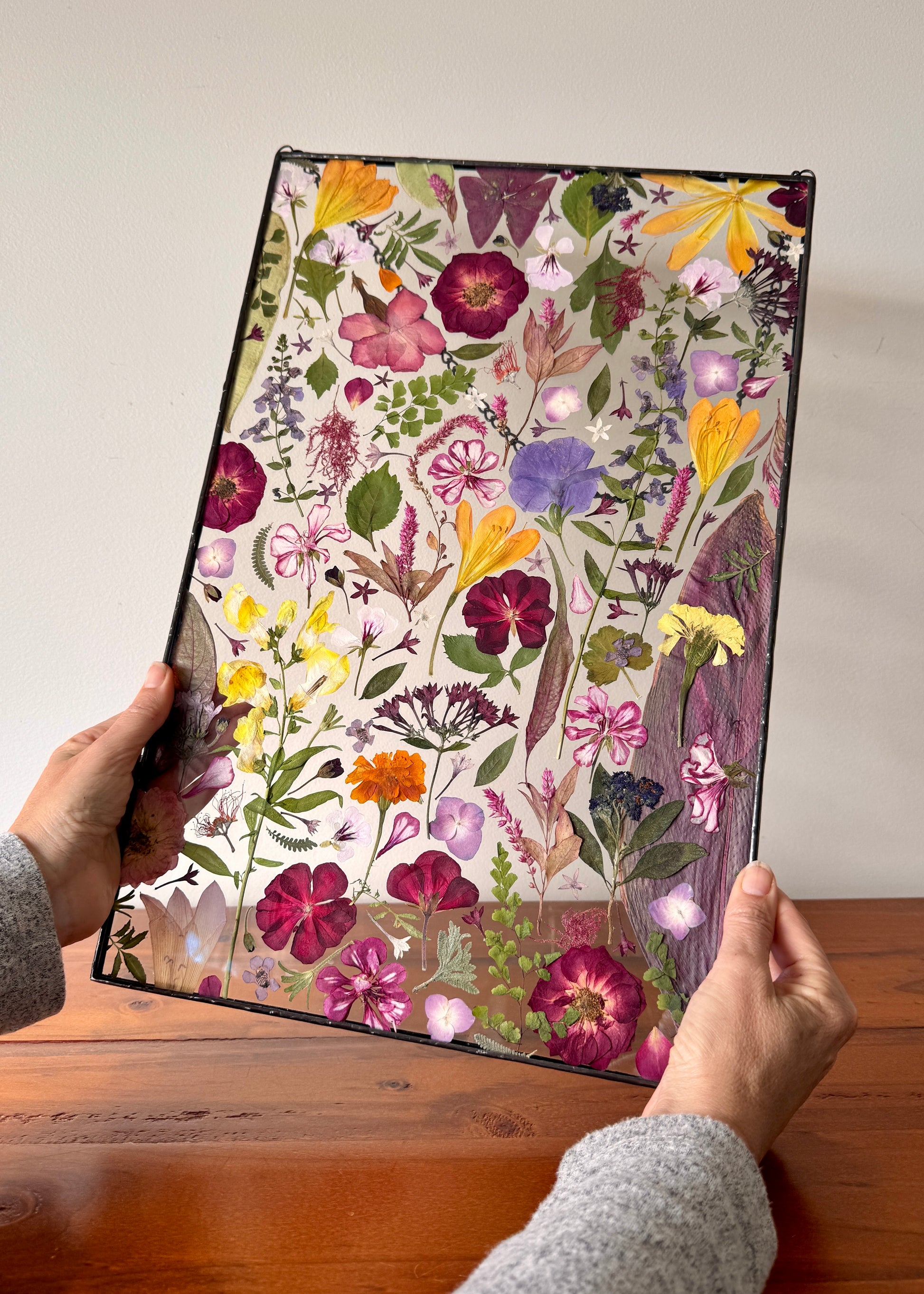 Floral patterned product held by a person on a wooden surface with a white background