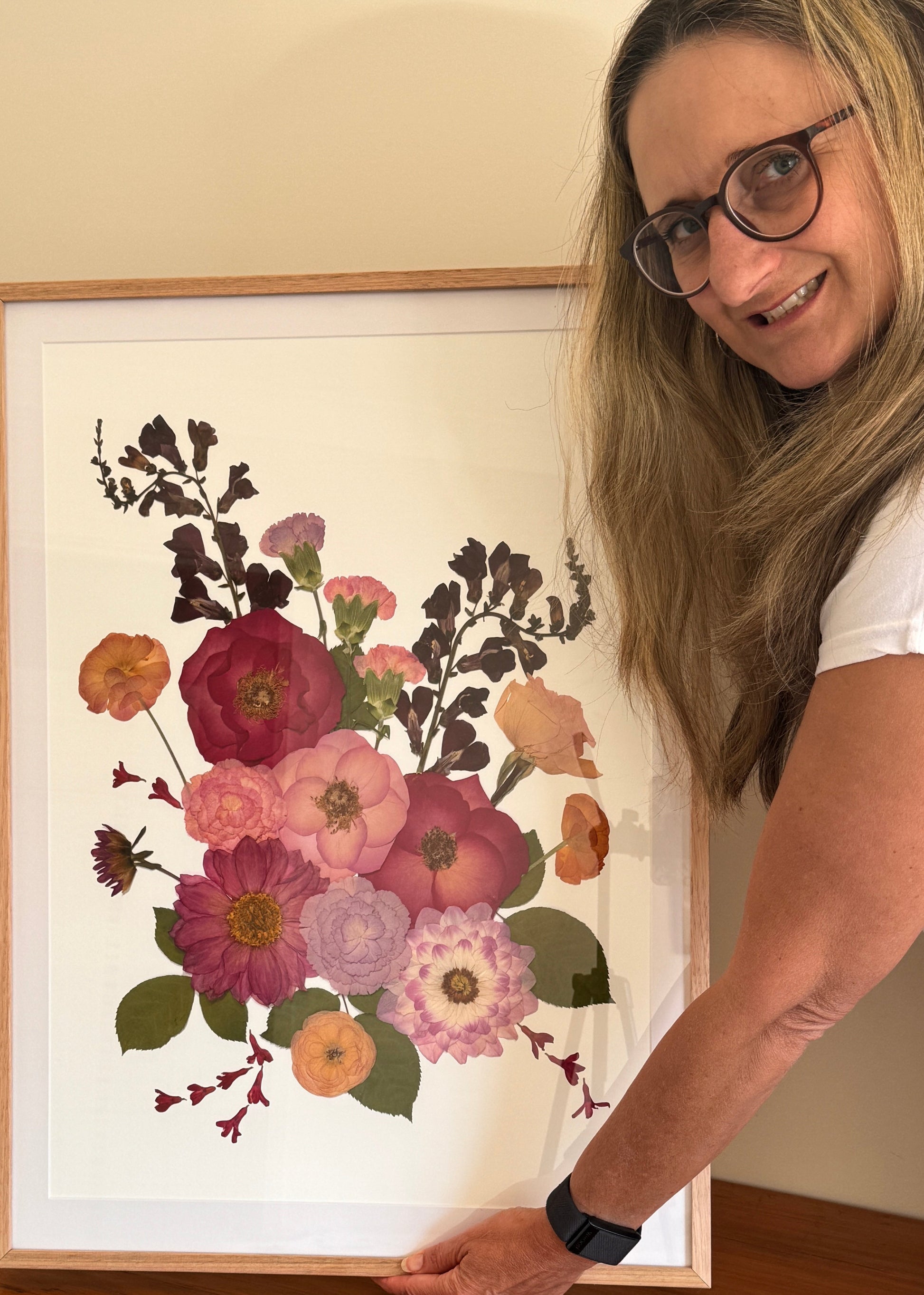 Joy van Niekerk from Created with joy Art holding a framed floral artwork