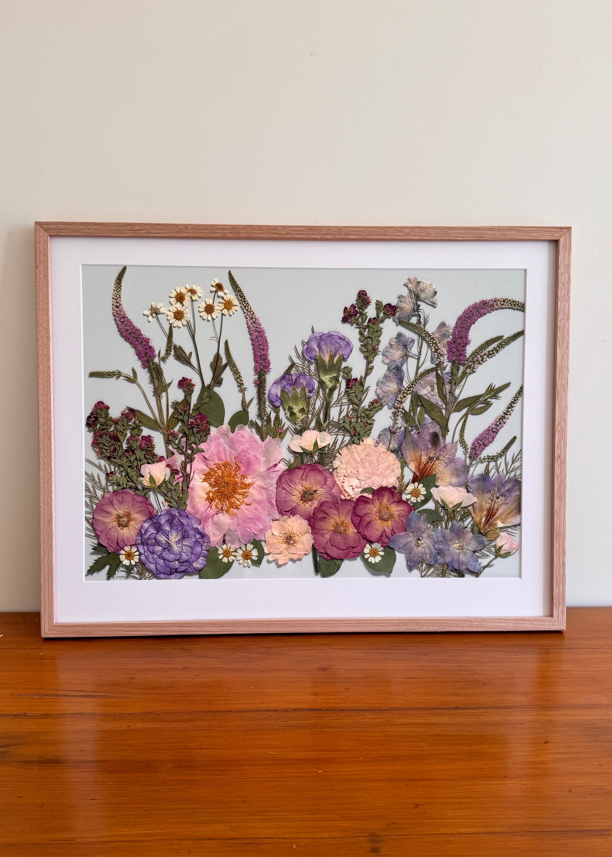Framed pressed flowers, veronicas and peony in shades of pink and purple, framed in a timber oak frame