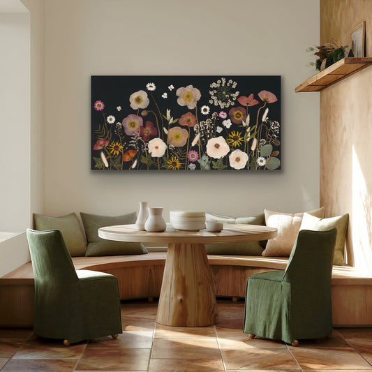 Living room with a round wooden table, green chairs, and a pressed flower artwork with black background on the wall.