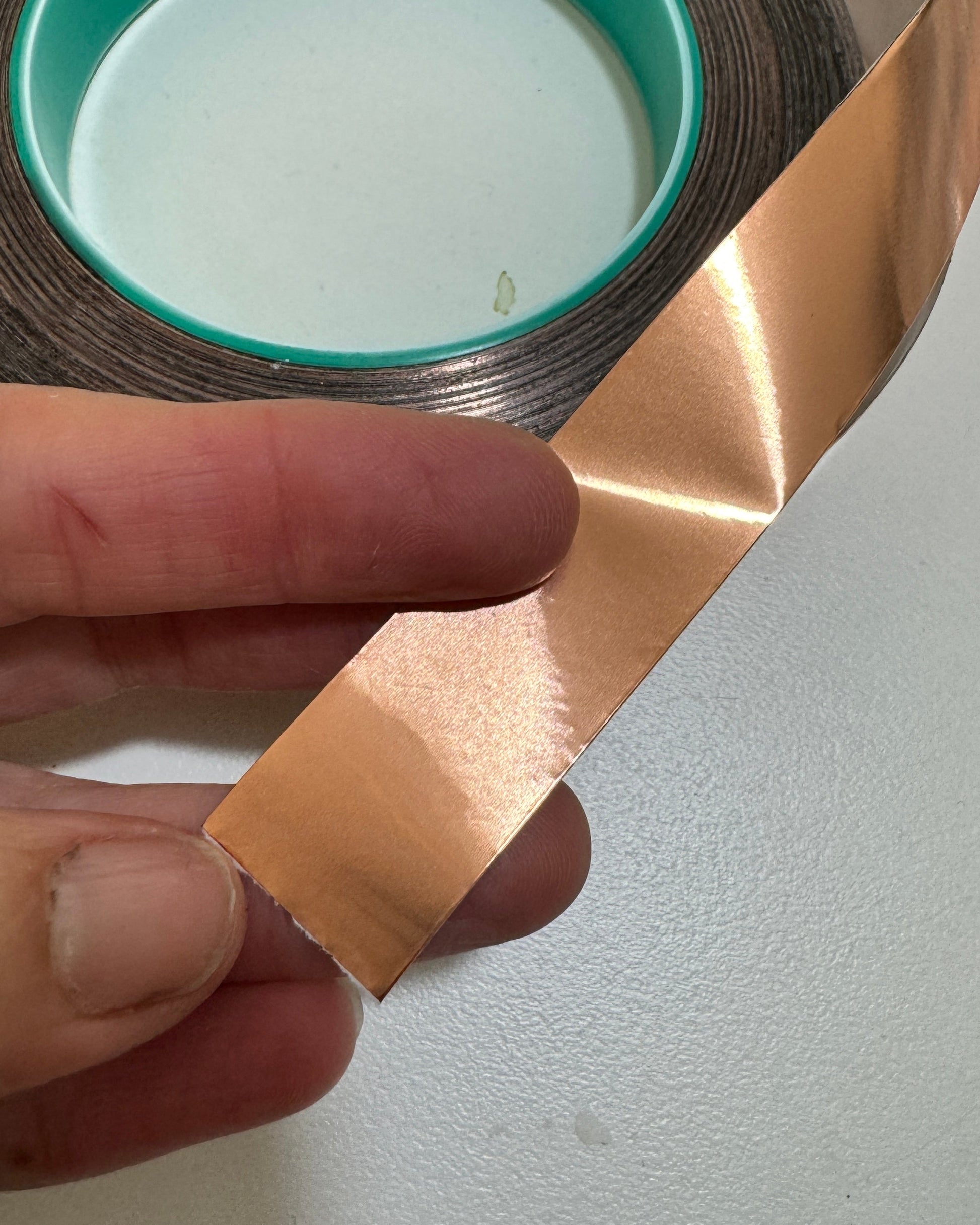 Person holding a strip of copperfoil tape against a white background