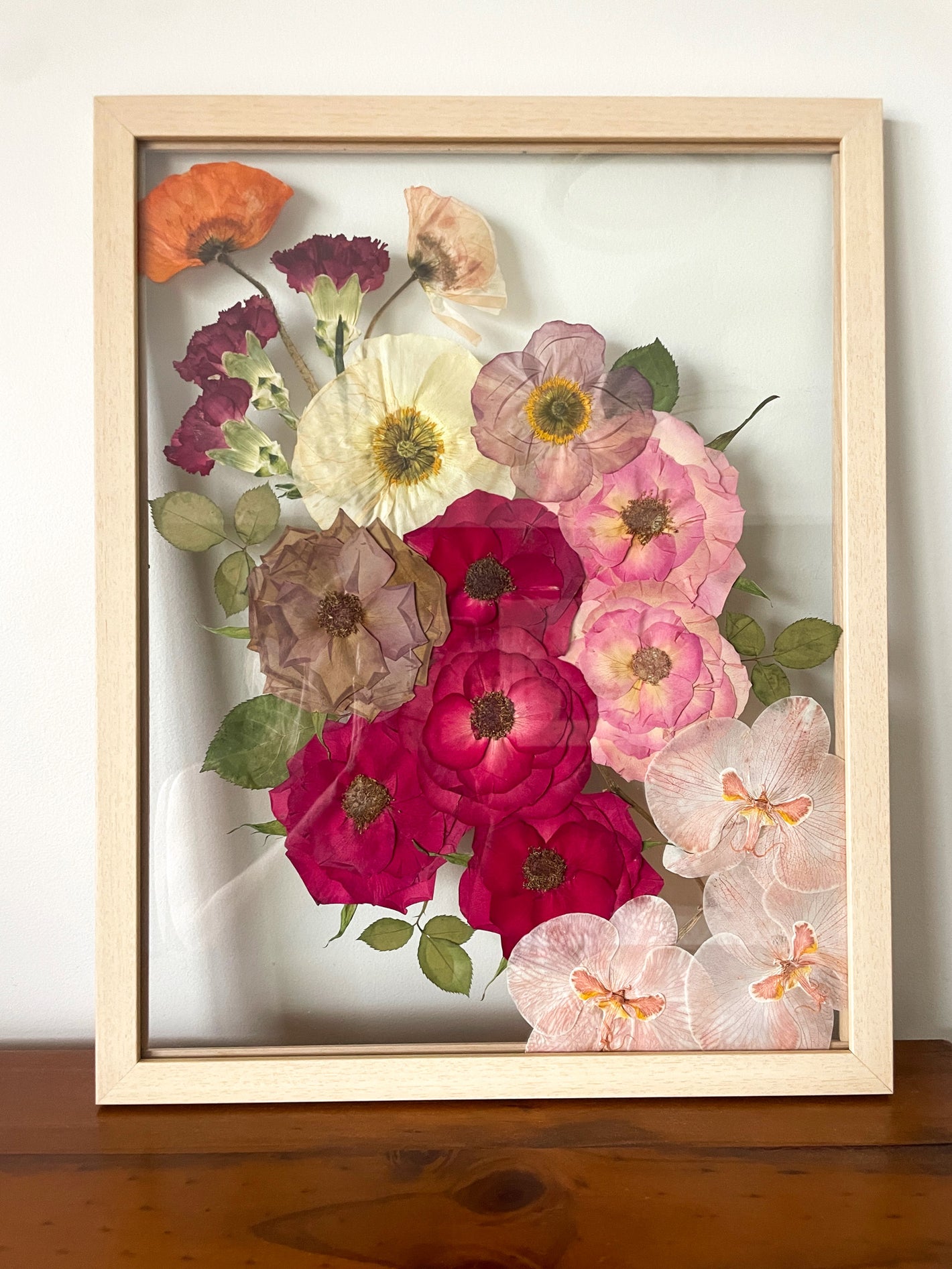 Preserved bridal bouquet of pressed red roses and orchids framed in timber frame. 