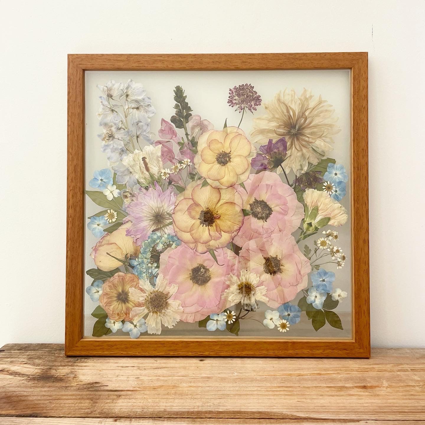 Custom timber-framed pressed flower artwork featuring colorful blooms.